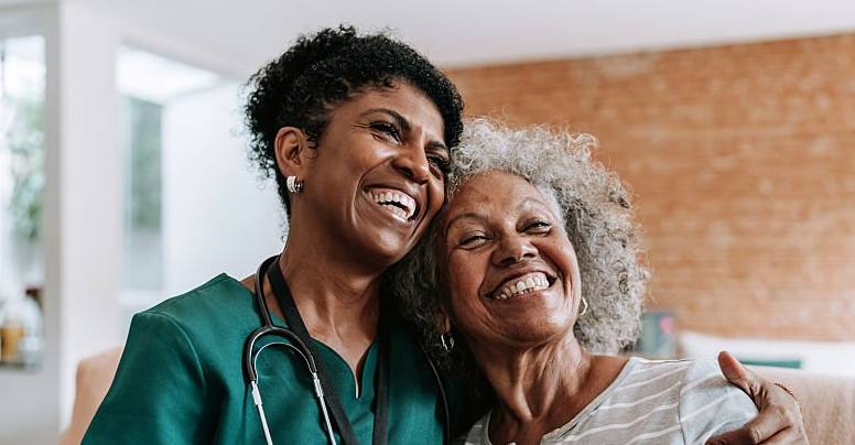 Warm caregiver embracing an elderly patient — both smiling — representing Safe Vision's family-centered compassionate care